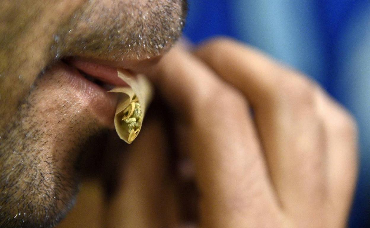 Un joven se hace un porro de marihuana. 