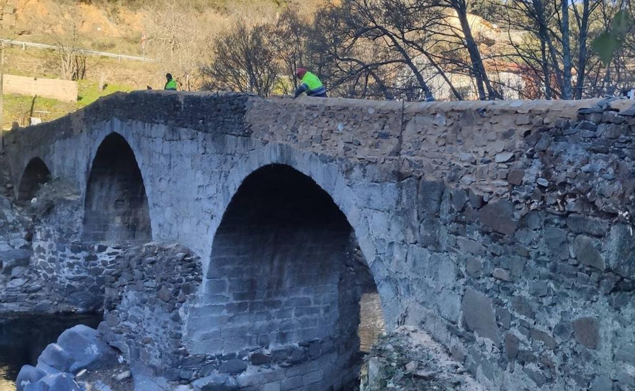 Los trabajadores realizando varios tramos nuevos de la pared del puente, que se ven más claros.
