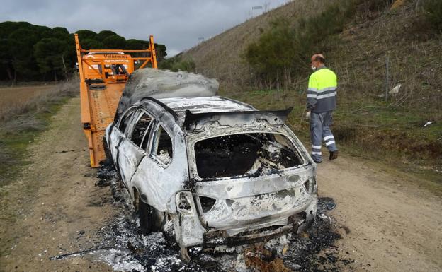 La grúa retira del vehículo destruido por las llamas..