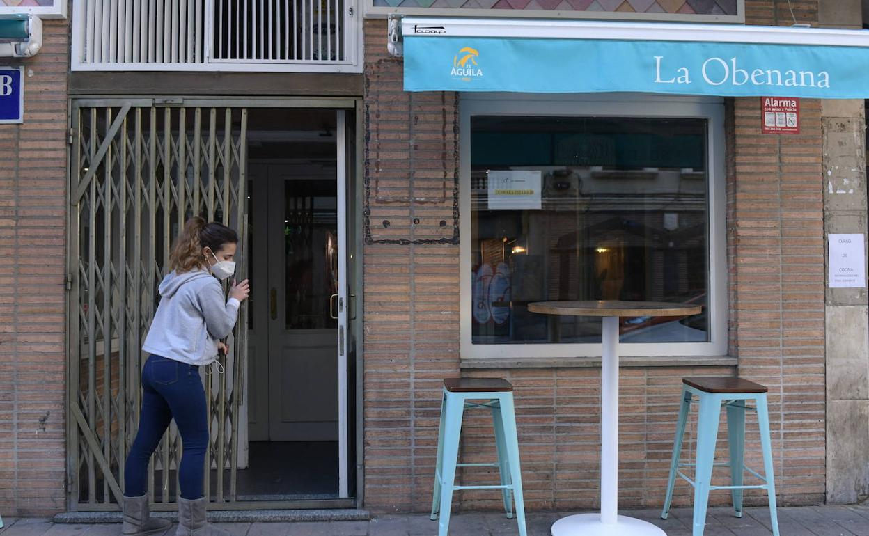 Una chica cierra la puerta de su bar. 