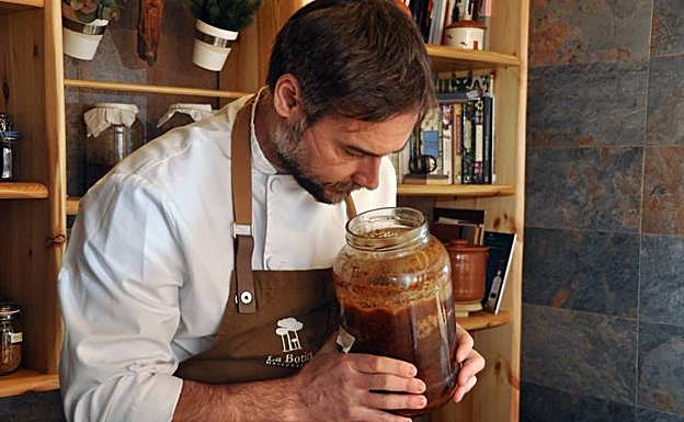 Imagen principal - Arriba, Miguel Ángel de la Cruz huele un gran tarro con jalea de piña verde, preparada por él. Abajo, varios tarros con vinagres y otros productos, y el chef en la cocina bilbaína. 