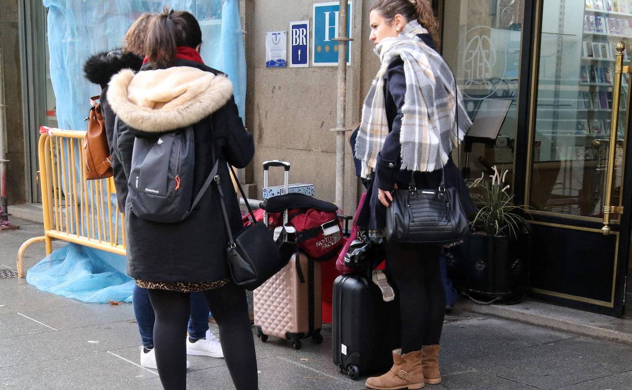 Tres turistas con maletas en la puerta de un céntrico hotel de Segovia durante la pandemia. 