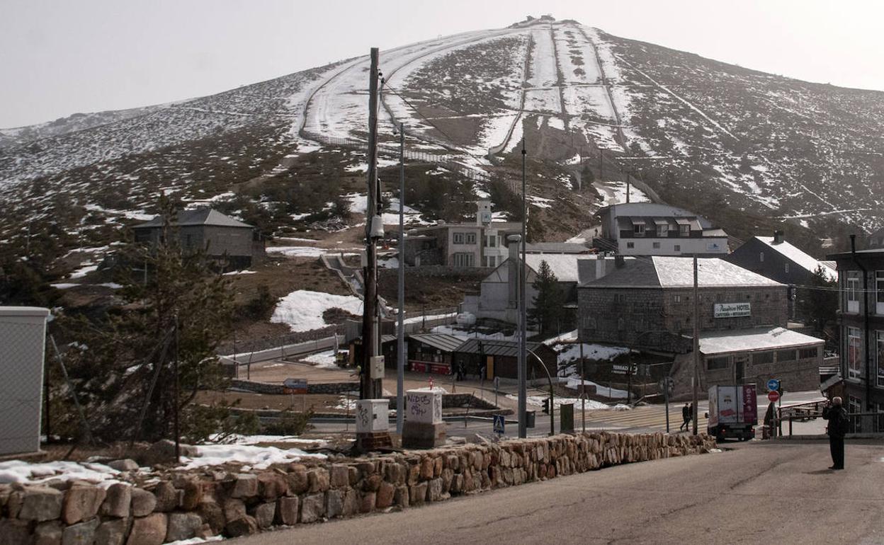 Complejo de tiendas y cafetería en el acceso a la estación, con las pistas de Guarramillas al fondo casi sin nieve este jueves. 