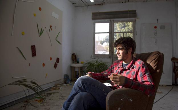 Imagen principal - Junto a una estufa de cáscaras de piñón, un viejo sofá, plantas y botes de colores tiene Eloy Arribas su hábitat creativo en el taller de Pedrajas.