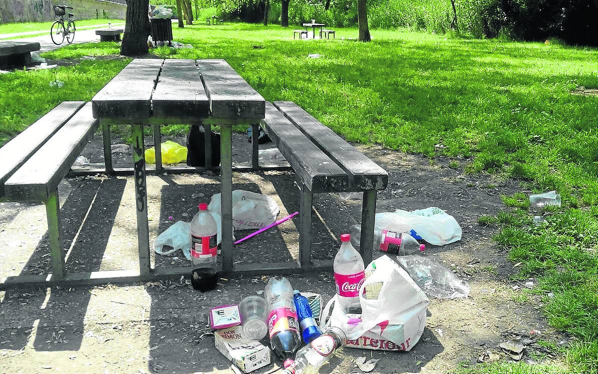 Restos de bebidas y basura acumulados junto a una de las mesas de recreo de la orilla del río Carrión.