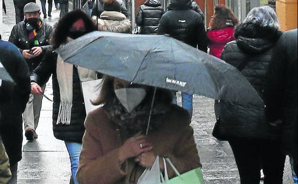 Transeúntes por la Calle Real de Segovia protegidos con ropa abrigo y paraguas, en la mañana de ayer. 