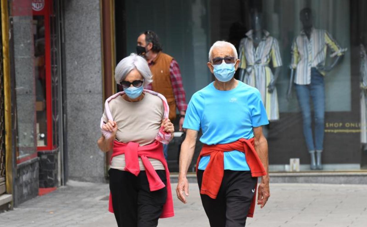 Dos viandantes pasean en manga corta por el centro de Valladolid. 