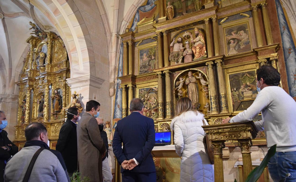 El viceconsejero de Cultura y otros representantes institucionales de la Junta observan un retablo y el altar en la visita a la iglesia restaurada. 