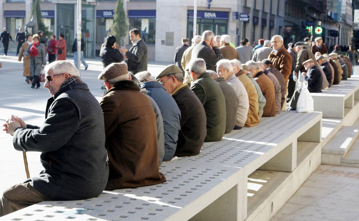 Varias personas mayores observan a los viandantes y charlan en la calle Santa Clara de Zamora.