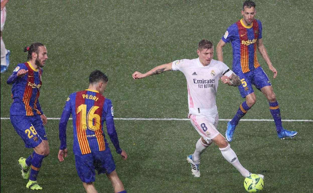 El centrocampista el Real Madrid Toni Kroos domina el balón entre tres los jugadores del Barcelona.