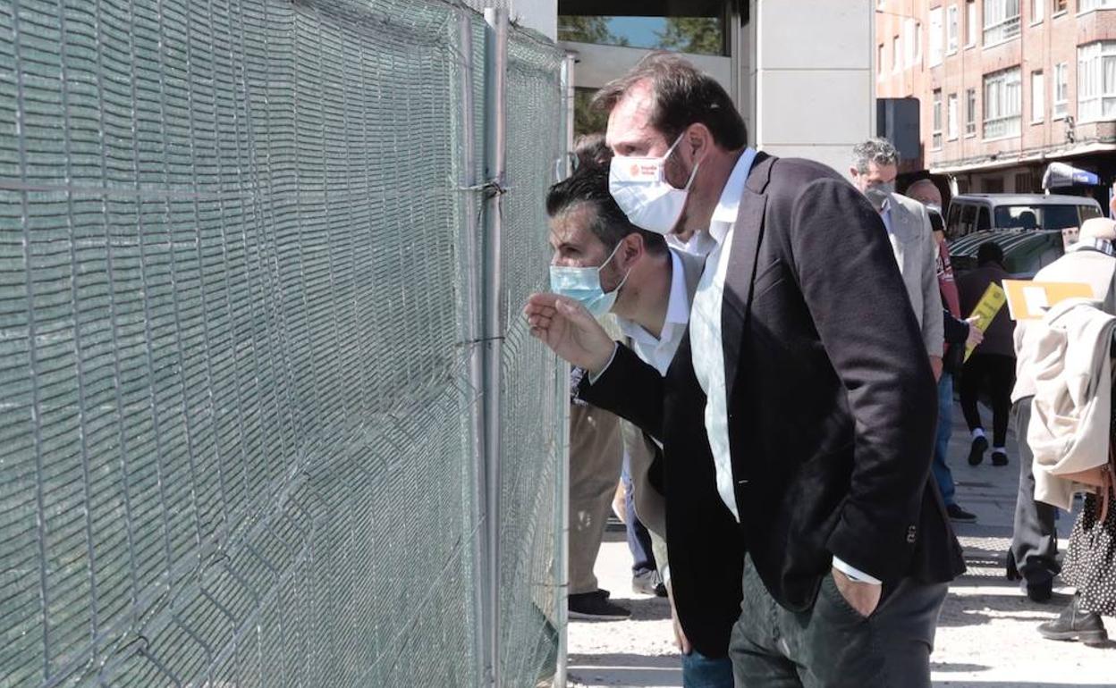 Luis Tudanca y Óscar Puente observan por un agujero en la valla las obras del túnel de Andrómeda. 