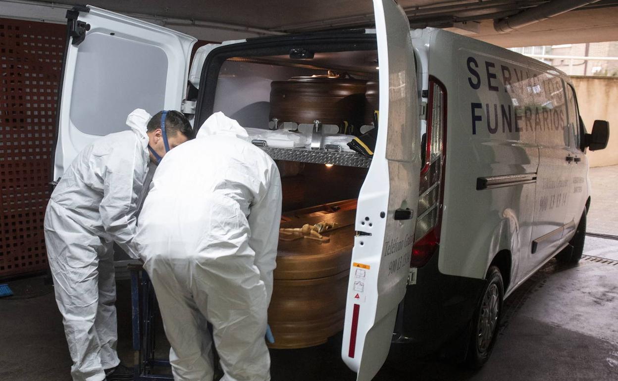 Servicios funerarios introducen un féretro en una furgoneta durante la pandemia en Segovia. 