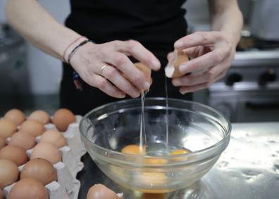 Imagen secundaria 1 - La tortilla de patatas paso a paso. Arriba, Ángel Galván corta las patatas a gran velocidad. Abajo, Tatyana Ivanova casca los huevos y, una vez batidos, los mezcla con la patata, previamnete frita. 