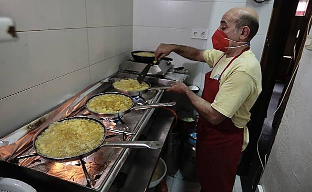 Ángel Galván, del bar El Postal, atiende a la vez cuarto fuegos con sartenes para cuatro tortillas de patatas. 