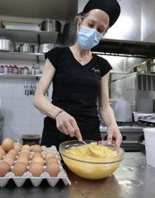 Imagen secundaria 2 - La tortilla de patatas paso a paso. Arriba, Ángel Galván corta las patatas a gran velocidad. Abajo, Tatyana Ivanova casca los huevos y, una vez batidos, los mezcla con la patata, previamnete frita. 