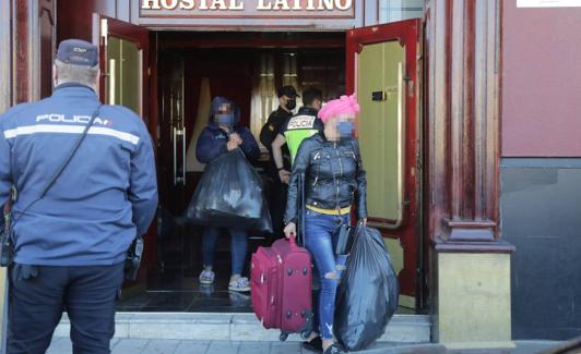 Dos mujeres salen con bolsas y maletas del club Latino. 