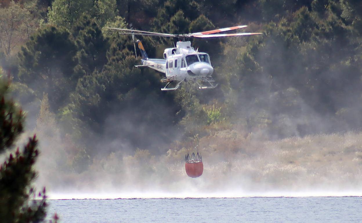 Un helicóptero coge agua para intentar sofocar el incendio. 