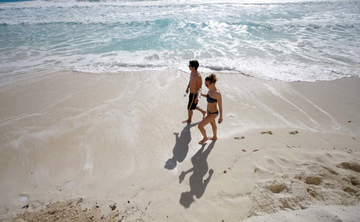 Una pareja camina por la playa.