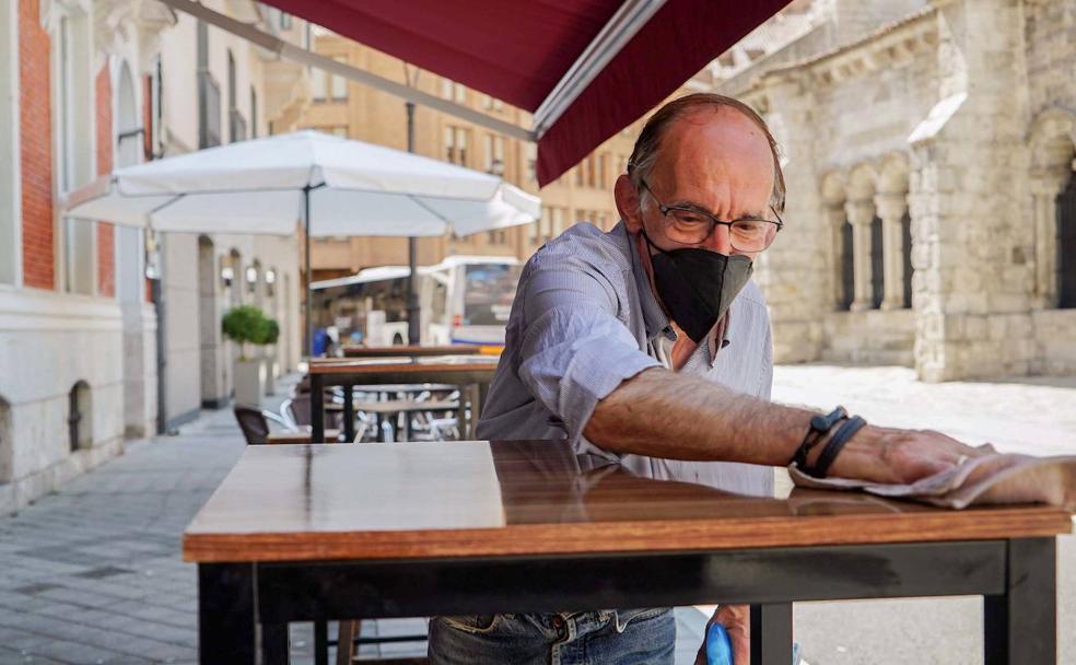 Carlos San Miguel 'Charly' limpia una mesa en la terraza del local donde trabaja.
