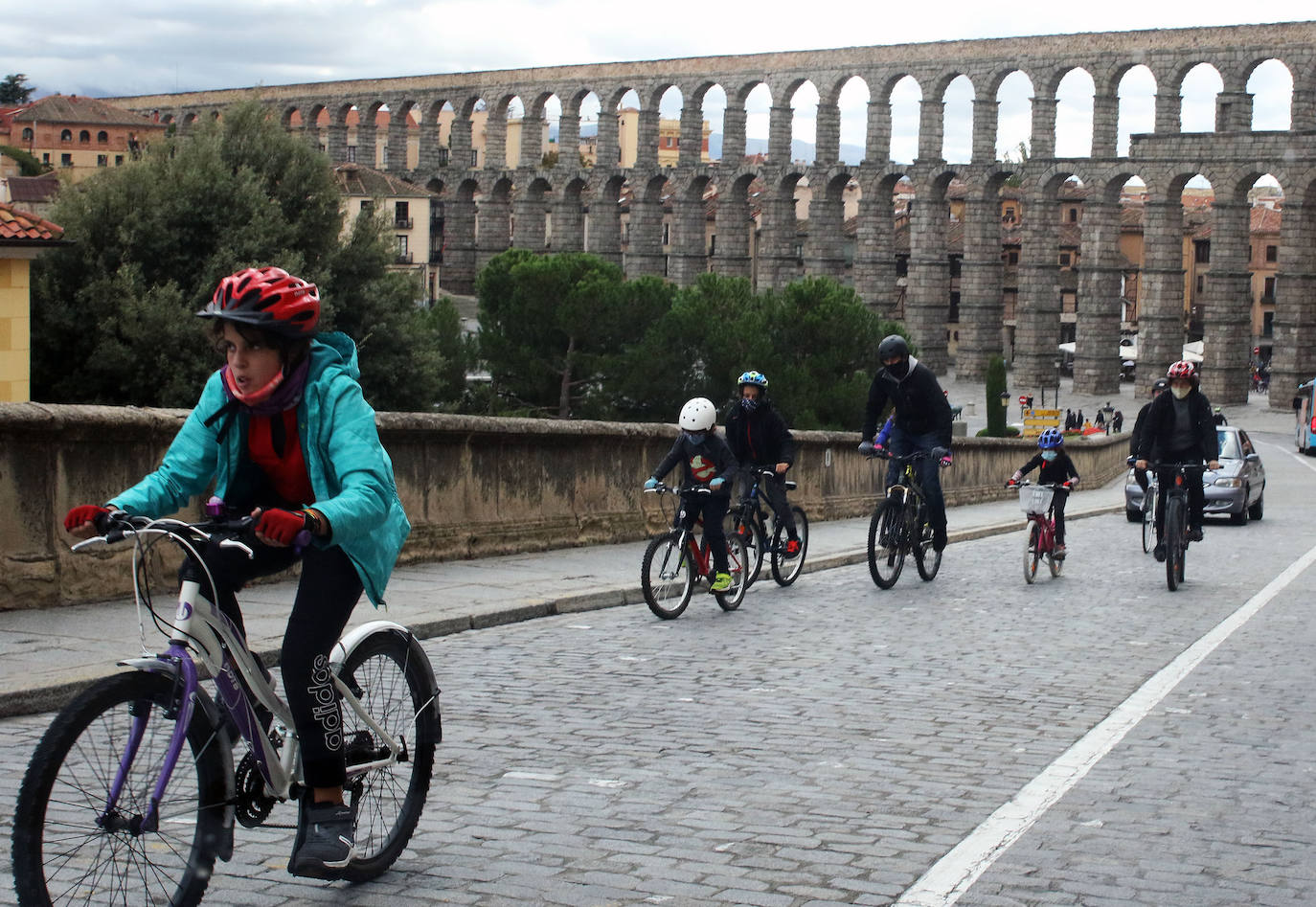 Un grupo de personas accede en bicicleta al recinto amurallado de Segovia a través de la calle San Juan.