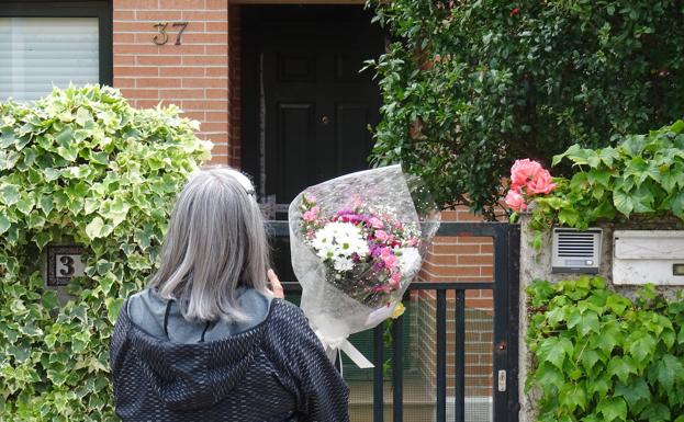 Una vecina observa las flores en la puerta de la casa de la víctima en la calle Montreal.