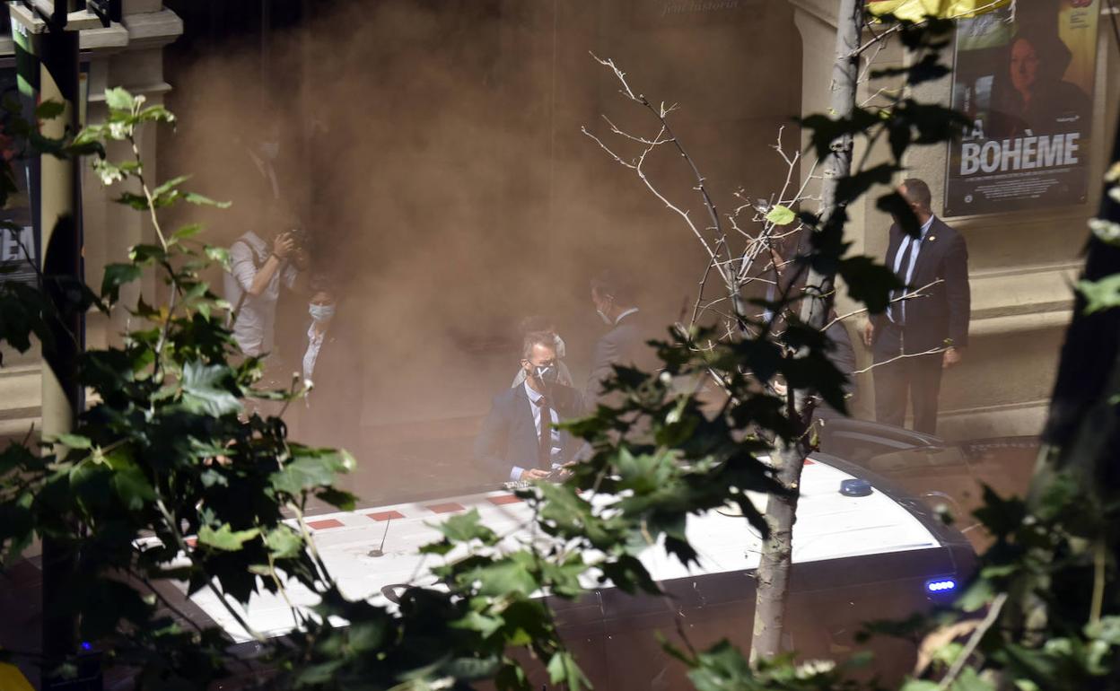 Pedro Sánchezentra al Teatro del Liceu entre el humo rojo de un bote lanzado por unos manifestantes, este lunes, en Barcelona.