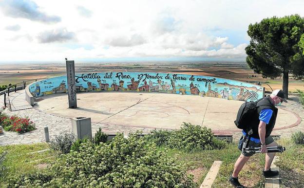 Un hombre con un trípode fotográfico abandona el acondicionado mirador de Autilla del Pino.