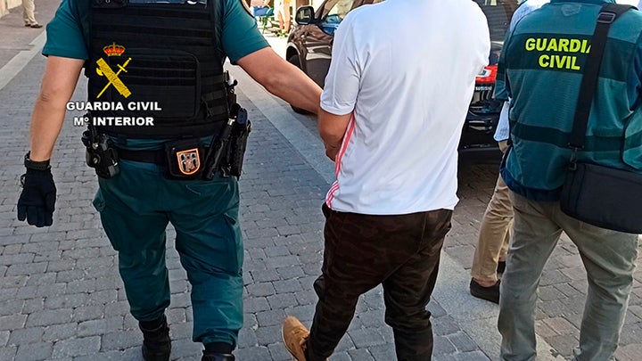 Un agente conduce esposado al sospechoso.
