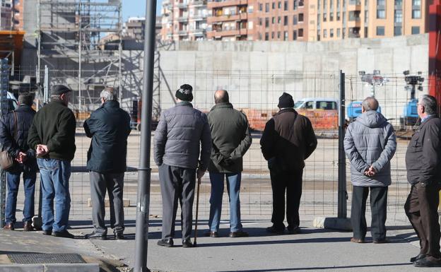 Un grupo de jubilados observa el trabajo en una obra. 