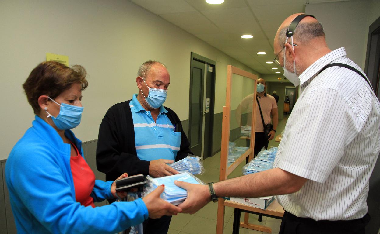 Dos personas recogen las mascarillas en el centro cívico de San José.