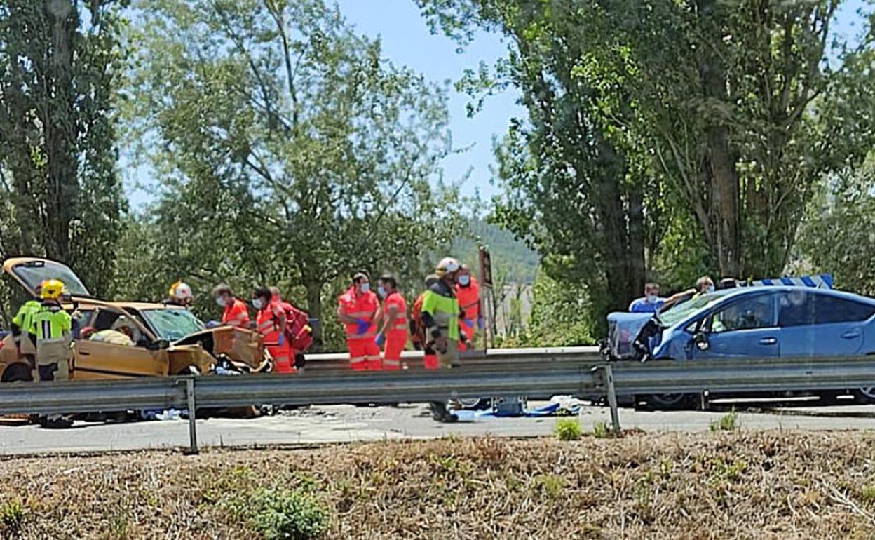 Los Bomberos y sanitarios trabajan tras la colisión entre los dos vehículos. I