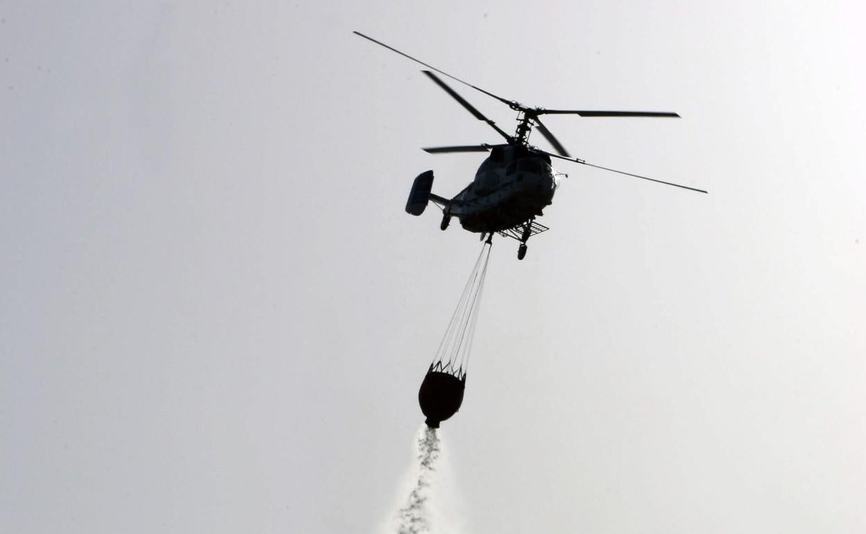 Foto de archivo - Un helicóptero suelta agua para sofocar un incendio. 