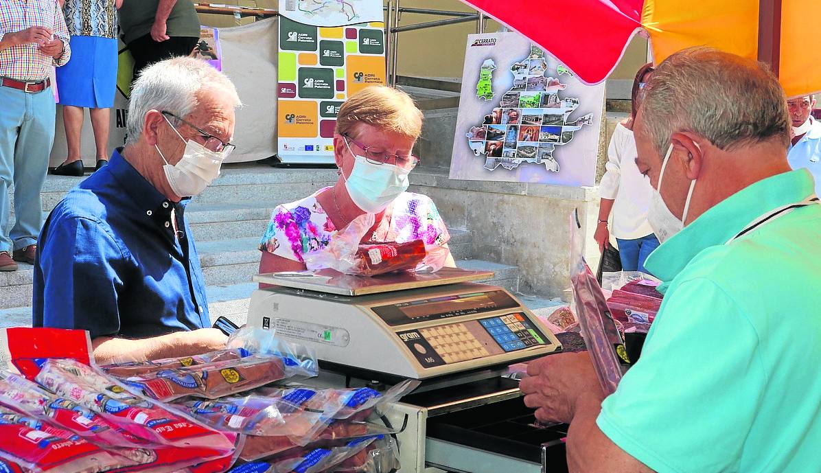 Dos personas compran embutido en un puesto. 