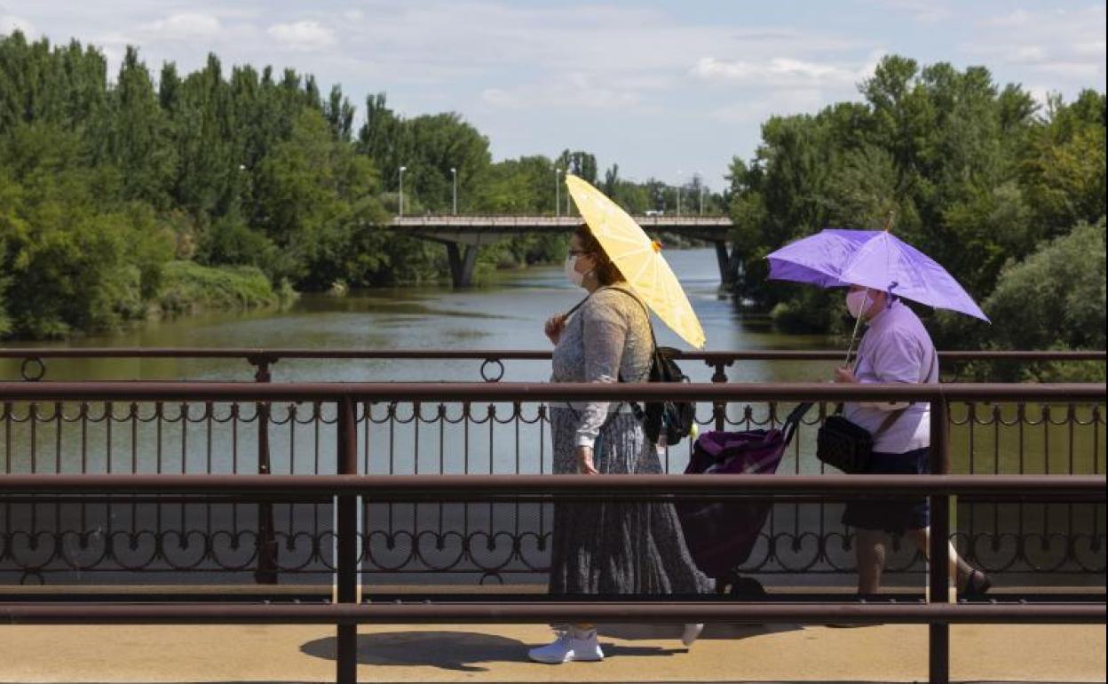 Dos mujeres se protegen del sol en el Puente Mayor.