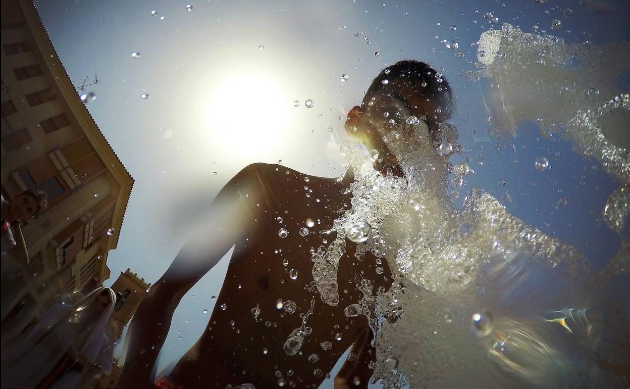 Un joven se refresca en una fuente. 