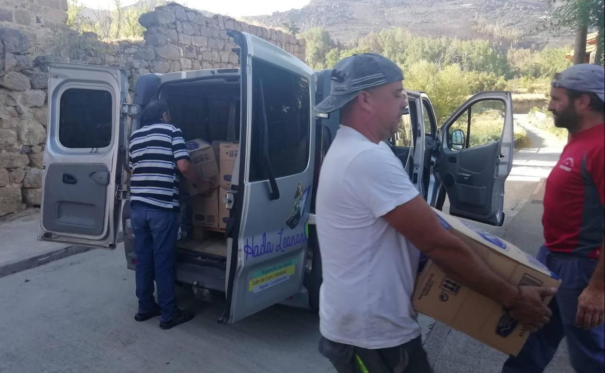 Voluntarios cargan garrafas de agua en una furgoneta en Ayllón para llevarla a Riofrío, una de las zonas afectadas por el fuego en Ávila. 