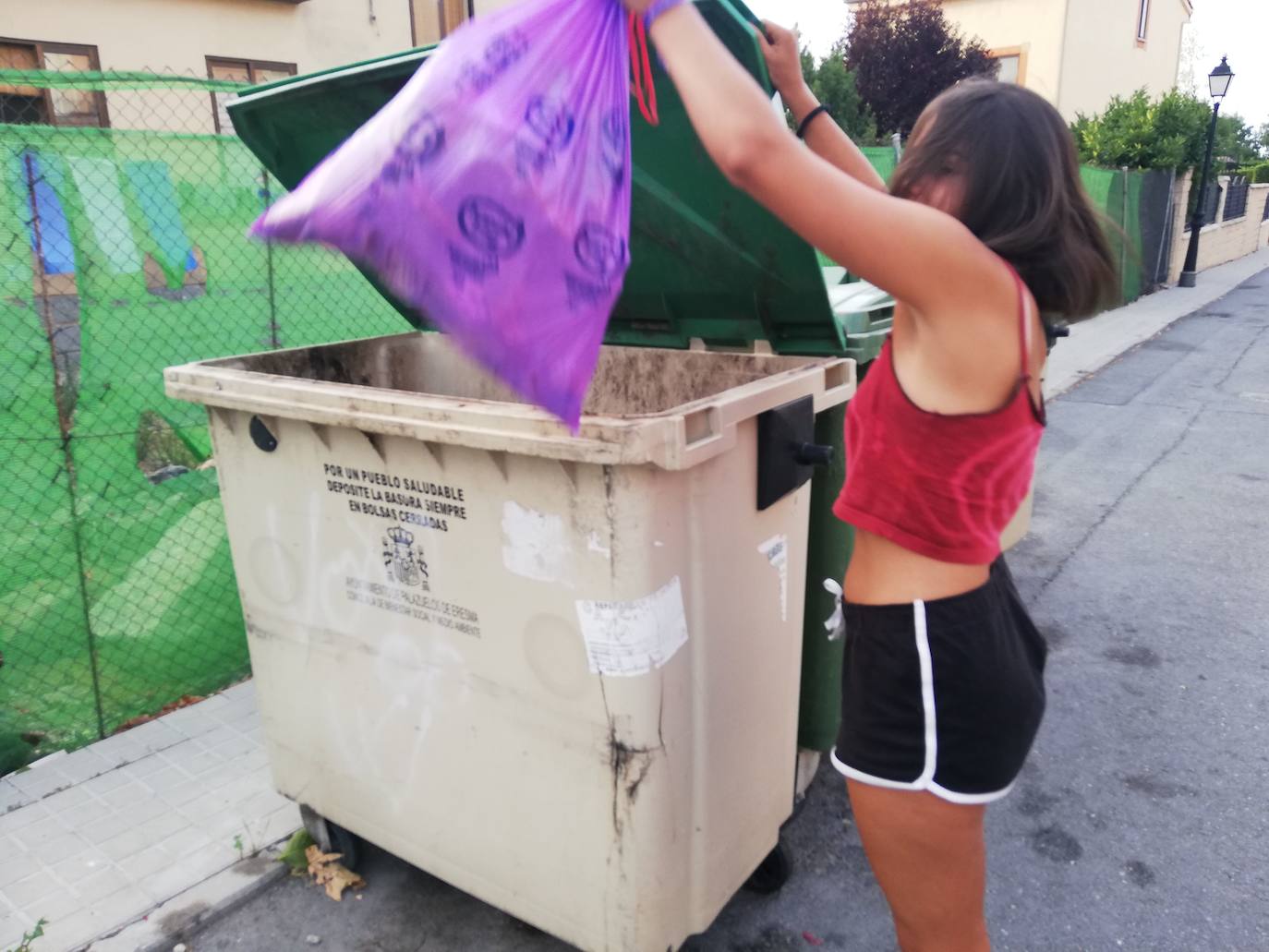 Una joven deposita la basura en un contenedor de Palazuelos de Eresma. 