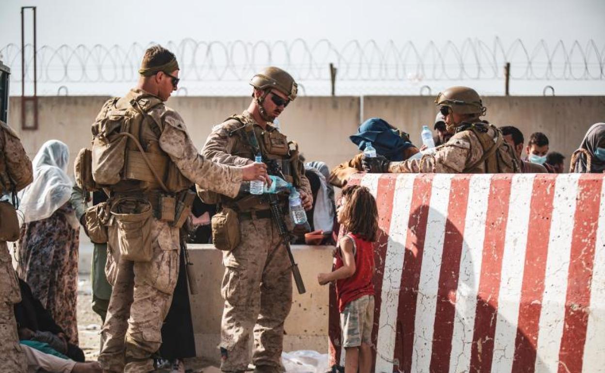 Soldados americanos entregan agua a una niña a las afueras del aeropuerto de Kabul, donde la muchedumbre se agolpa para intentar huir del país.