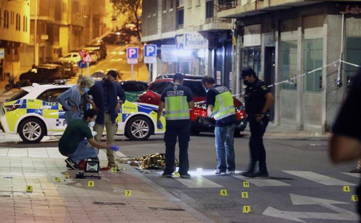 Agentes policiales en el lugar del asesinato, con el cuerpo del fallecido aún en el suelo.