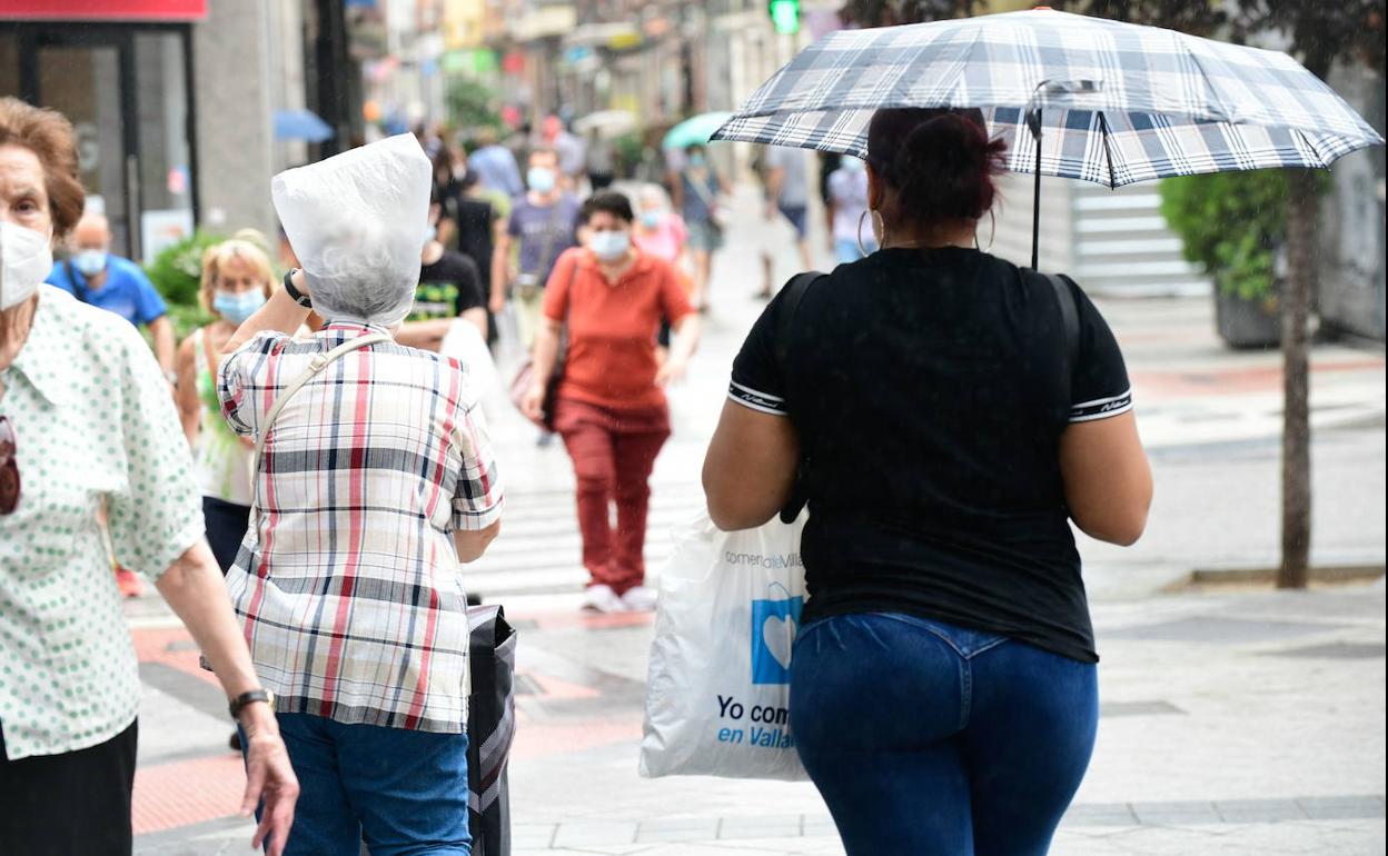 Varias personas se protegen de la lluvia en Valladolid capital durante una tormenta del pasado verano.