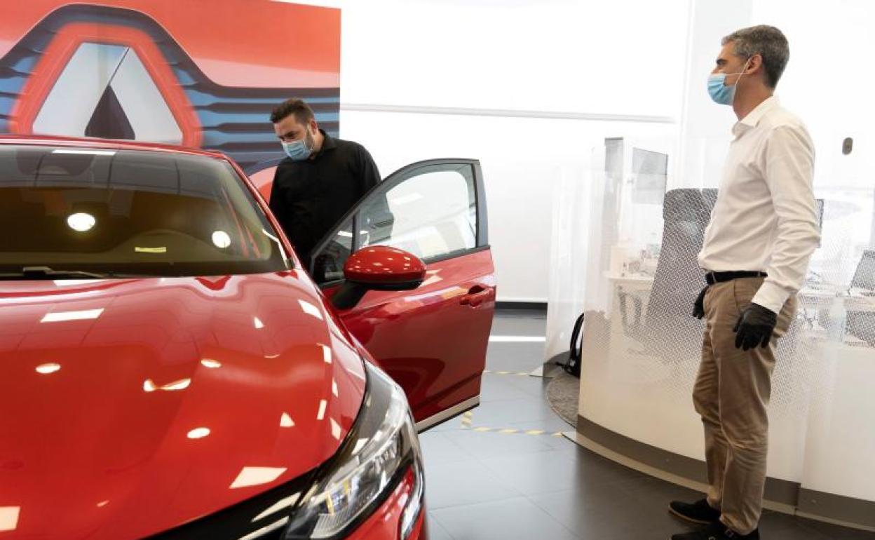 Un cliente observa un coche en presencia de un comercial en un concesionario de Renault. 