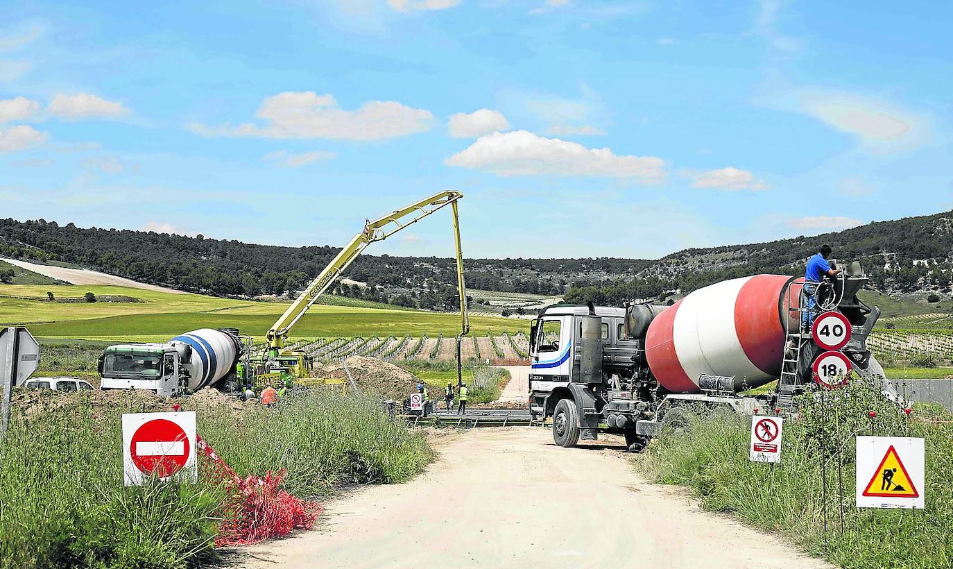 Operarios con camiones de hormigón durante los trabajos de construcción de la Autovía del Duero y una de las infraestructuras levantadas.