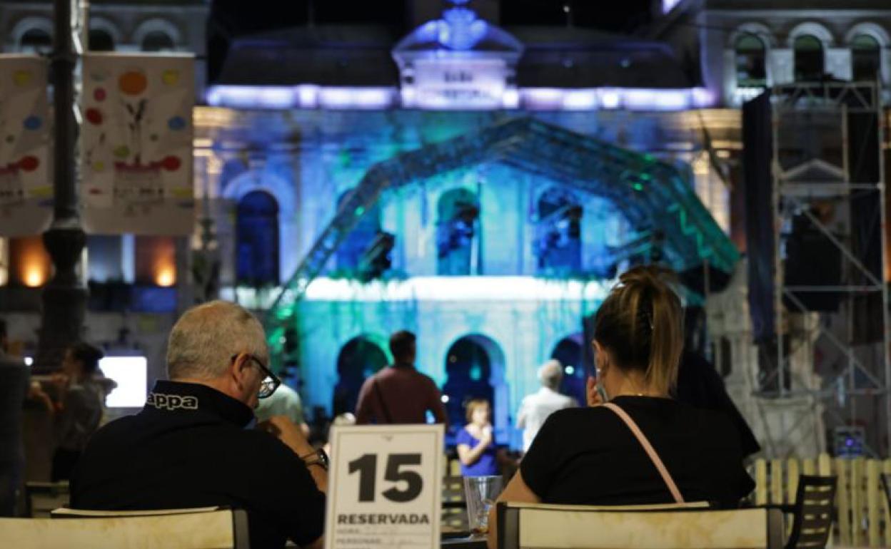 Dos usuarios disfrutarn de uno de los conciertos de fiestas en una terraza de la Plaza Mayor.