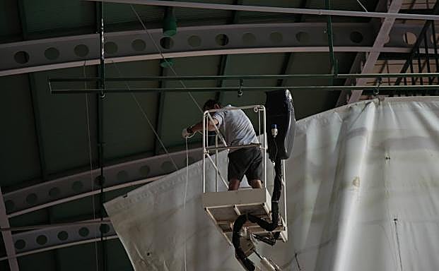 Un operario repara la lona que cayó a la cancha.
