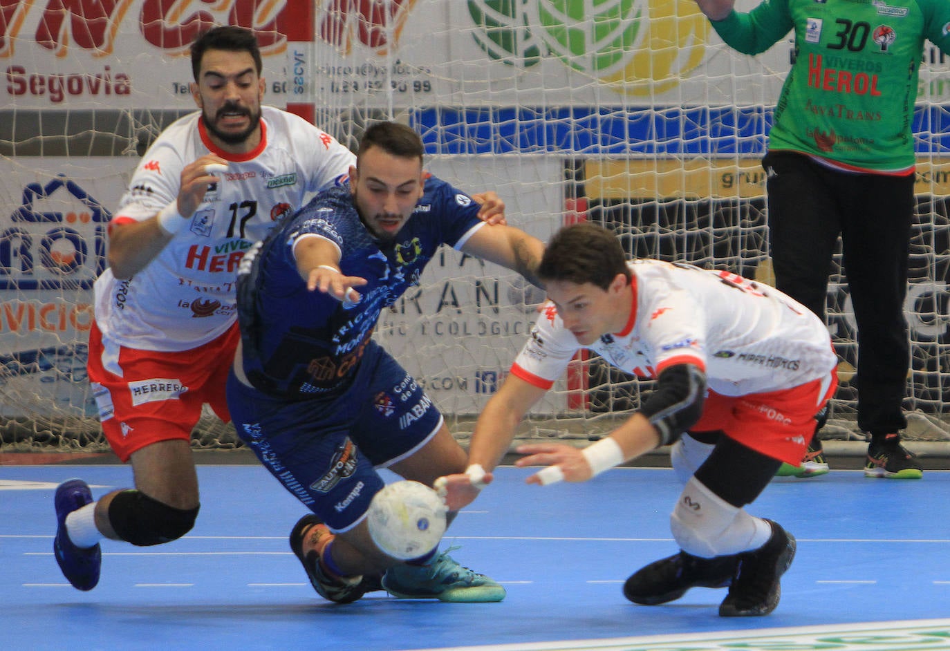 Tres jugadores se lanzan al suelo para disputar una pelota suelta durante el partido en Nava de la Asunción.