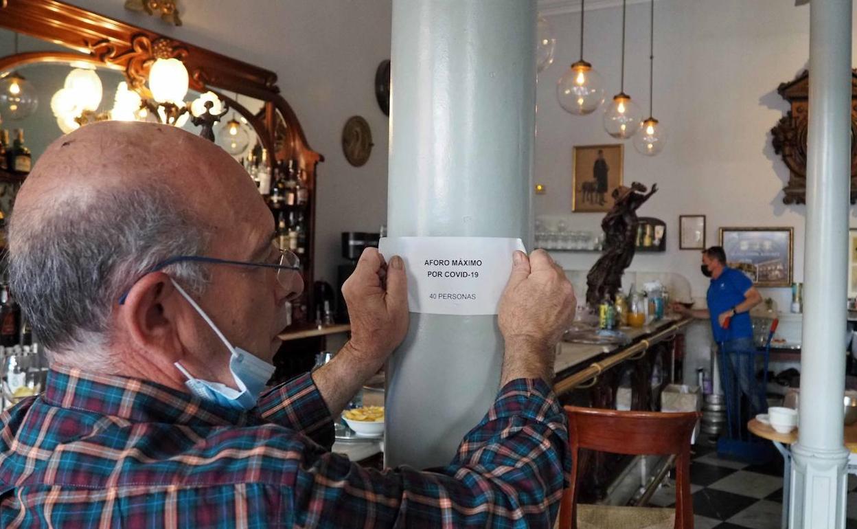 Colocación del nuevo cartel de aforo en una cafetería de Valladolid. 