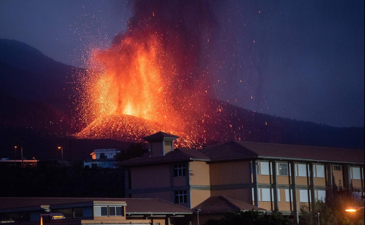 Imagen de la erupción del volcán detrás de unos edficios.