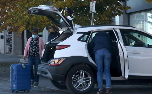 Unos turistas cargan las maletas en el coche. 