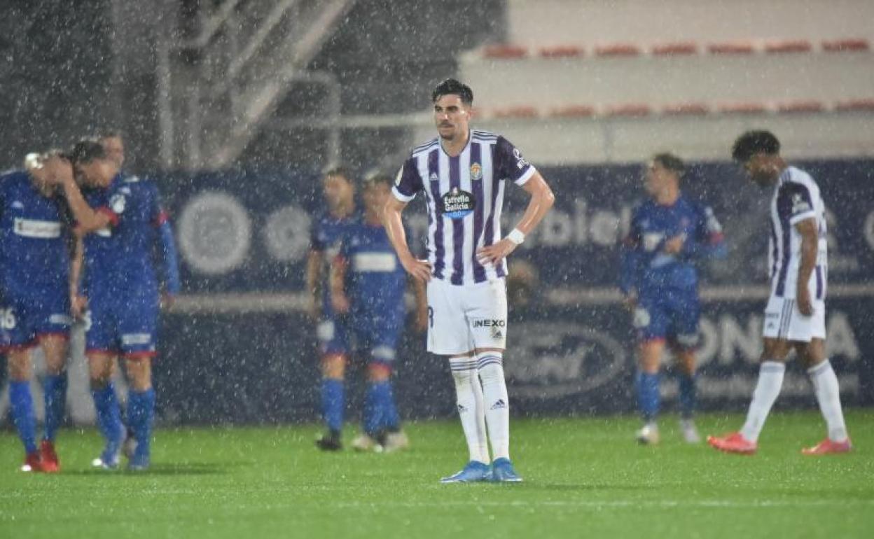 Kike Pérez, abatido como el resto de jugadores del Real Valladolid, mientras los futbolistas del Amorebieta celebran el triunfo.