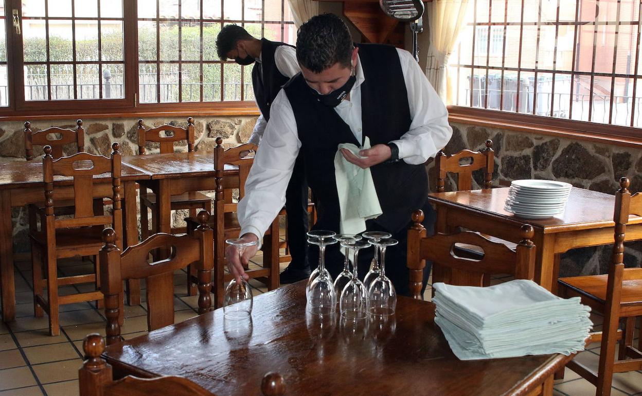 Unos camareros preparan las mesas para los comensales en un restaurante de Segovia. 